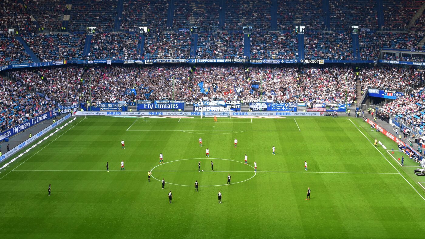 A stadium during a match, seen from the stands in late-afternoon light.