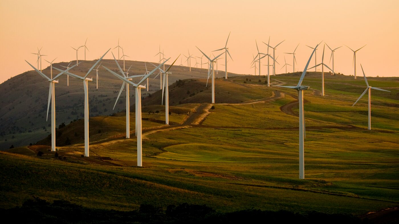 A wind farm following the ridge of green hills.
