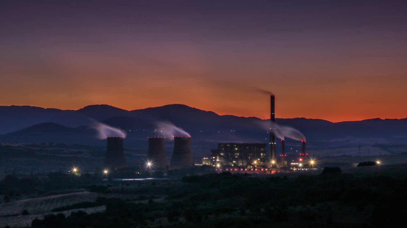 A thermal power station at dusk beneath an orange sky.